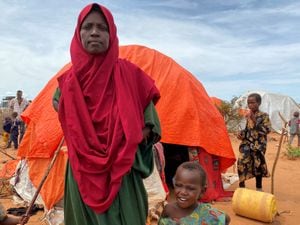 Khadijo Mohamed Omar, 35, poses for a photograph with one of her surviving children outside her dome-shaped home made of sticks and orange fabric at the Ladan camp for internally displaced people (IDP) in Dollow, Somalia May 1, 2023. REUTERS/Ayenat Mersie