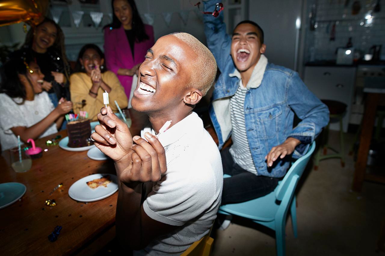 Excited young man celebrating birthday with friends during party at home