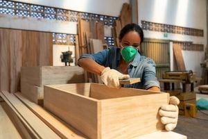 Mujer latinoamericana que trabaja en una fábrica de muebles y lija la madera - conceptos de fabricación