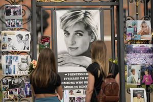 Dos mujeres miran los retratos de la princesa Diana y otros recuerdos expuestos en las puertas del Palacio de Kensington, en Londres, el martes 30 de agosto de 2022. Esta semana se cumple el 25 aniversario de la muerte de la princesa Diana en un accidente automovilístico en París. Foto AP/Alastair Grant