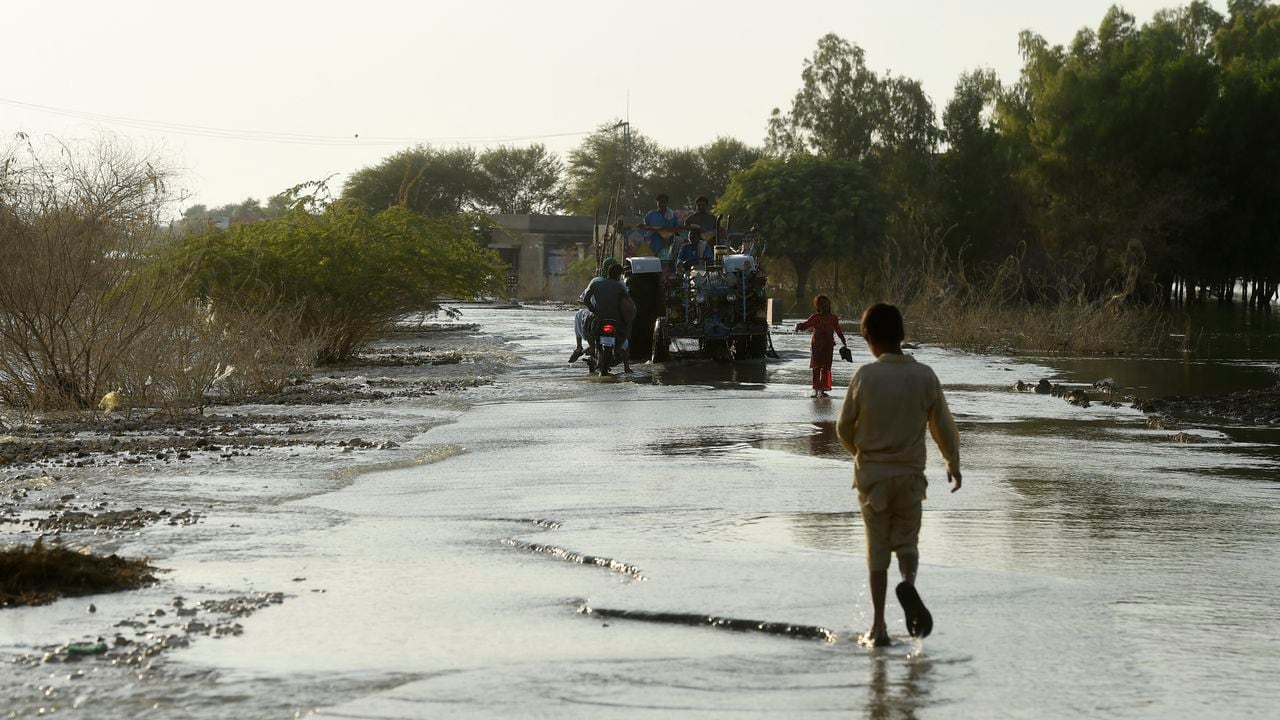Los desplazados internos caminan por un área inundada en Dadu, en la provincia de Sindh, el 27 de octubre de 2022. (Foto de Asif HASSAN / AFP)