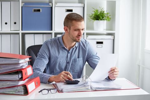 Empresario pensativo calcula impuestos en un escritorio en la oficina. Hombre hace cuentas