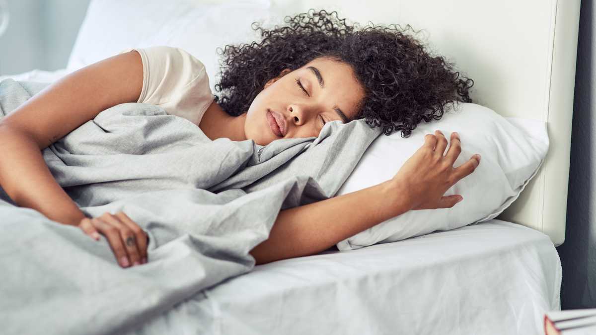 Foto de una mujer joven durmiendo plácidamente en su cama