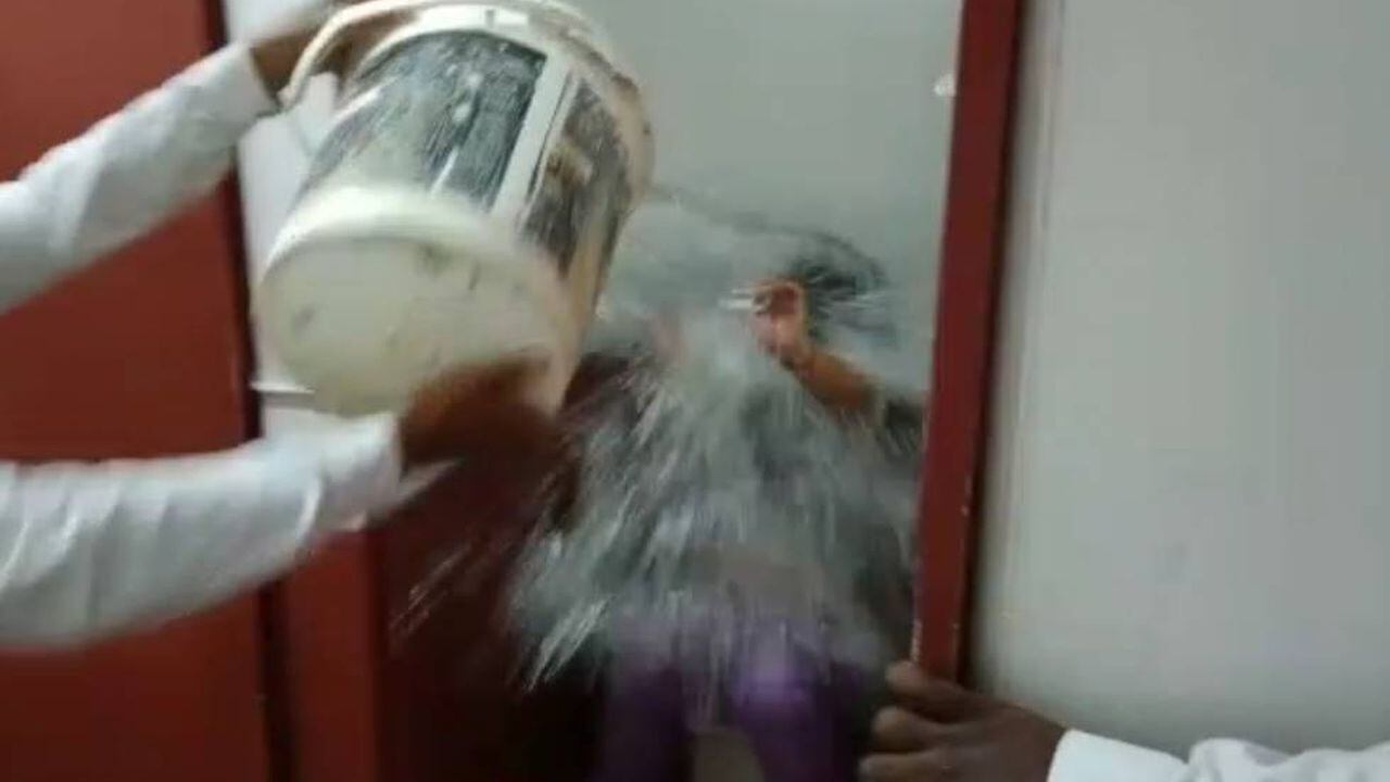 Momento en que los guardas de seguridad echan agua a mujer en baño de Cali
