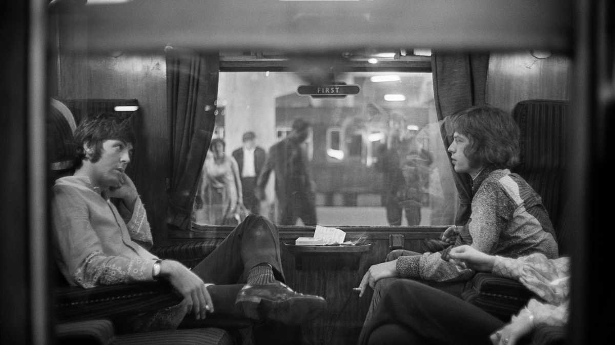 25th August 1967:  Paul McCartney of the Beatles and Mick Jagger of the Rolling Stones sit opposite each other on a train at Euston Station, waiting for departure to Bangor.  (Photo by Victor Blackman/Express/Getty Images)