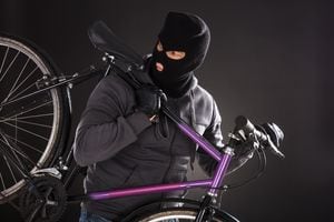 Person Wearing Balaclava Stealing A Bicycle On Black Background