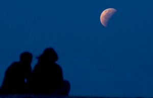 A couple watch the lunar eclipse at Sanur beach in Bali, Indonesia on Wednesday, May 26, 2021. (AP Photo/Firdia Lisnawati)