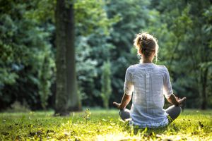 Joven mujer rubia meditando en el parque