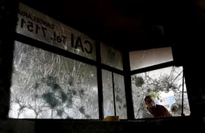 A man looks into a police post damaged by protesters the previous night in Bogota, Colombia, Wednesday, May 5, 2021. Protests that began last week over a tax reform proposal continue despite President Ivan Duque's withdrawal of the tax plan from congress on Sunday, May 2. (AP Photo/Fernando Vergara)