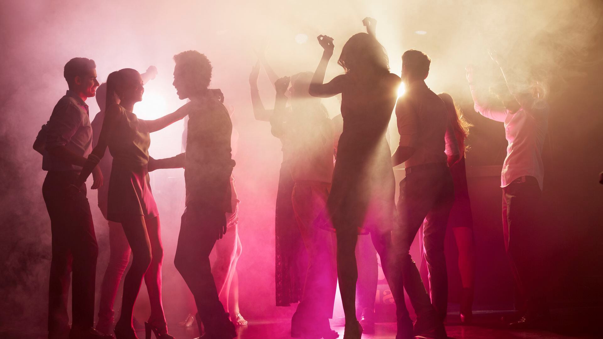Group of people dancing on dance floor at nightclub