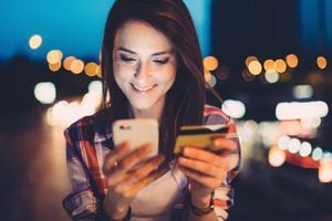 Smiling woman outside at night shopping online with credit card
