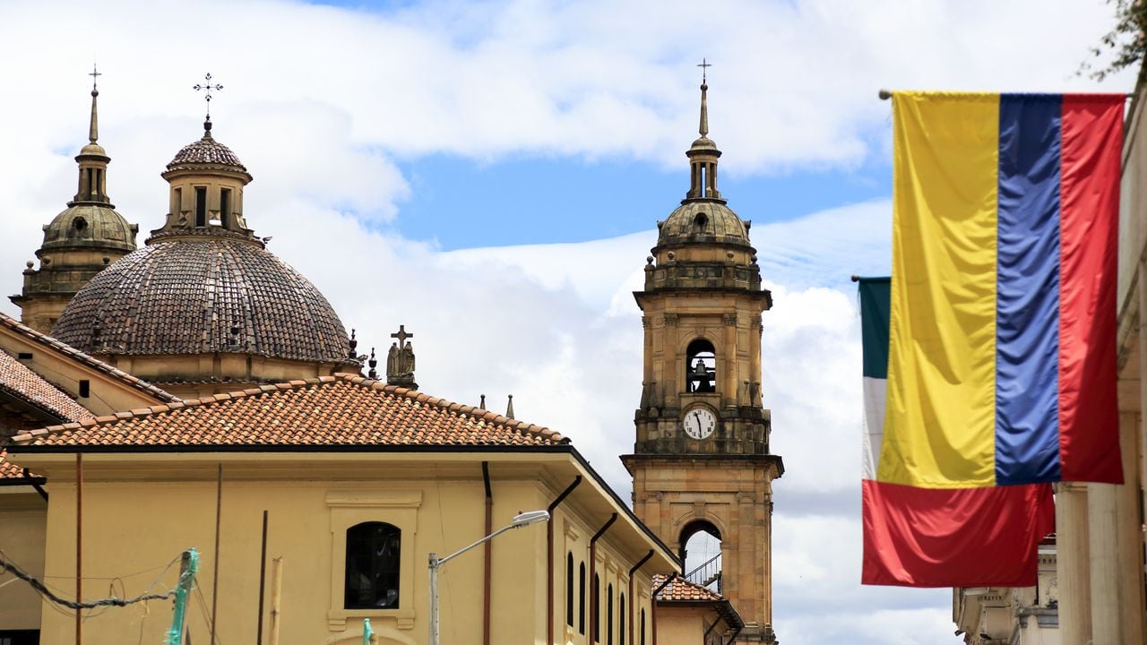 The view of the dome and bell towers of Primatial Cathedral of Bogota (Metropolitan Cathedral Basilica of the Immaculate Conception) in La Candelaria the historical center of Bogota with Colombian flag in foreground. Bogota.Colombia. 05/2017