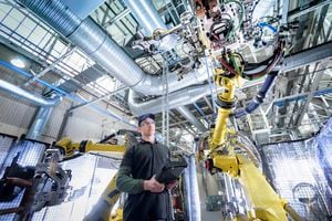 Aprendiz de ingeniero ajustando robot en fábrica de automóviles - Imagen de referencia