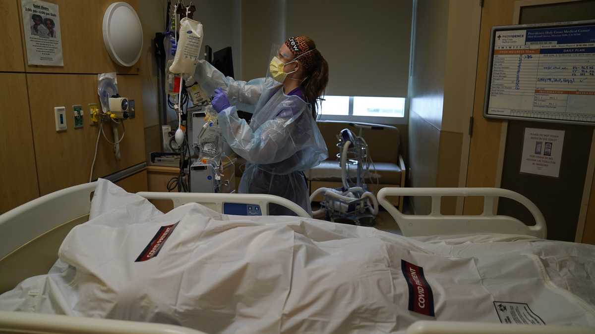 La enfermera Nikki Hollinger limpia una habitación frente al cuerpo de una víctima de covid-19 en un centro médico de Los Ángeles. (AP Foto/Jae C. Hong)