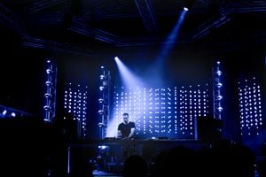 Dj playing techno music on the stage during night concert.