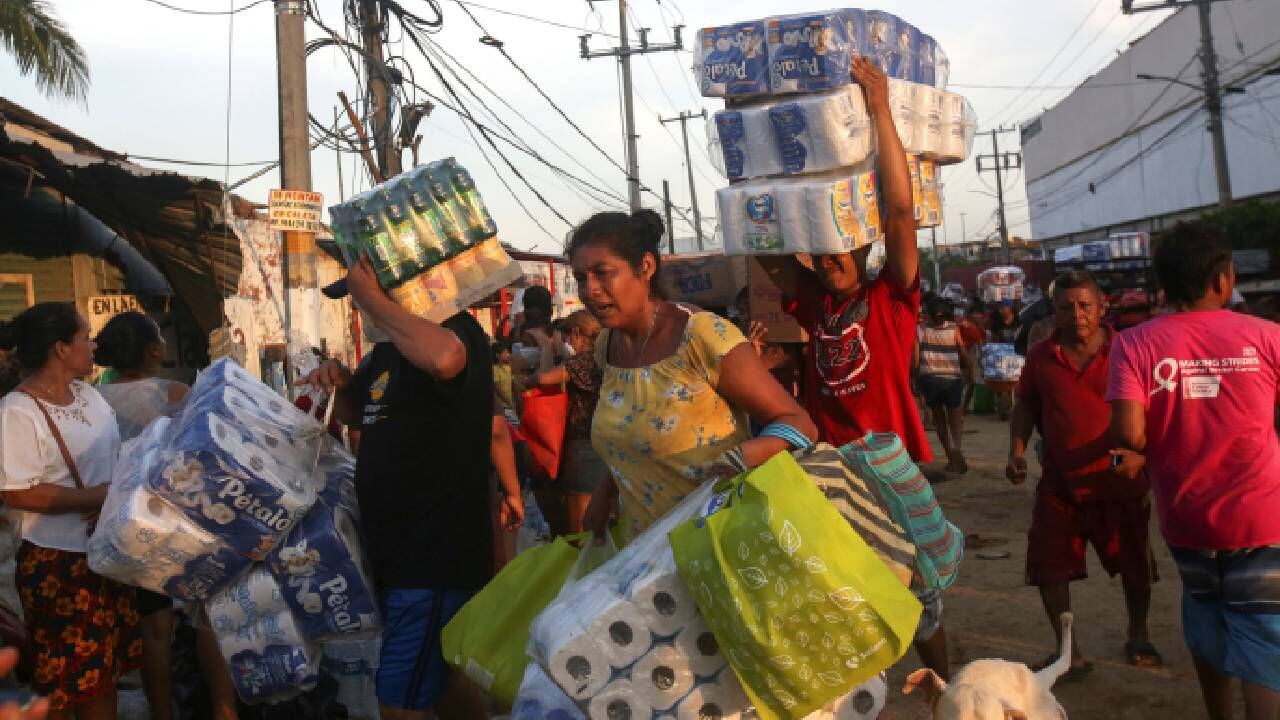 La gente lleva artículos que han tomado de un supermercado, después del huracán Otis.