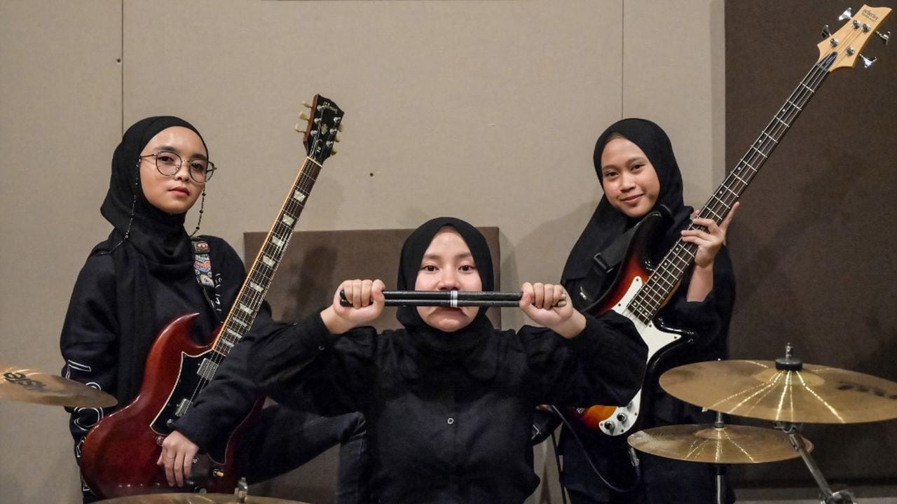 En esta foto tomada el 8 de abril de 2021, los miembros de la banda indonesia de heavy metal Voice of Baceprot (VOB), la guitarrista y vocalista Firda Marsya Kurnia (izq.), la baterista Euis Siti Aisah (c) y la bajista Widi Rahmawati (der.) posan para las fotos después de una sesión de práctica en Yakarta. Foto de Bay Ismoyo / AFP)
