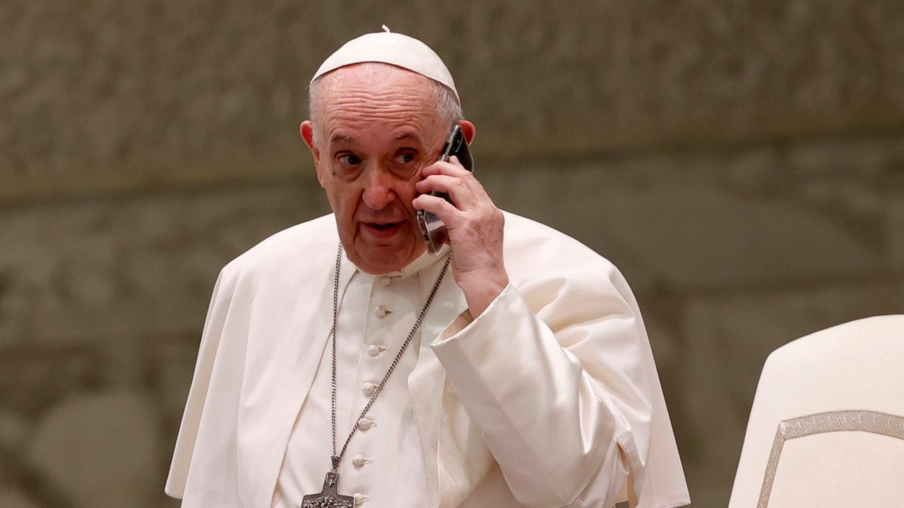 El Papa Francisco habla por un teléfono celular, que le dio su asistente Piergiorgio Zanetti, al final de su audiencia general semanal en la sala Pablo VI del Vaticano, el miércoles 11 de agosto de 2021 (AP Photo / Riccardo De Luca).