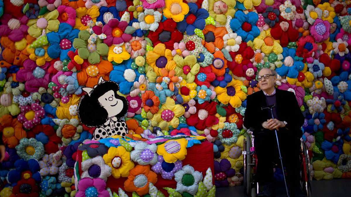 FILE - In this Sept. 15, 2014 file photo, Argentine cartoonist Joaquin Salvador Lavado, better known as "Quino," poses next to his character Mafalda at the exhibition, The World According to Mafalda, in Buenos Aires, Argentina. Lavado passed away on Wednesday, Sept. 30, 2020, according to his editor Daniel Divinsky who announced it on social media. (AP Photo/Natacha Pisarenko, File)