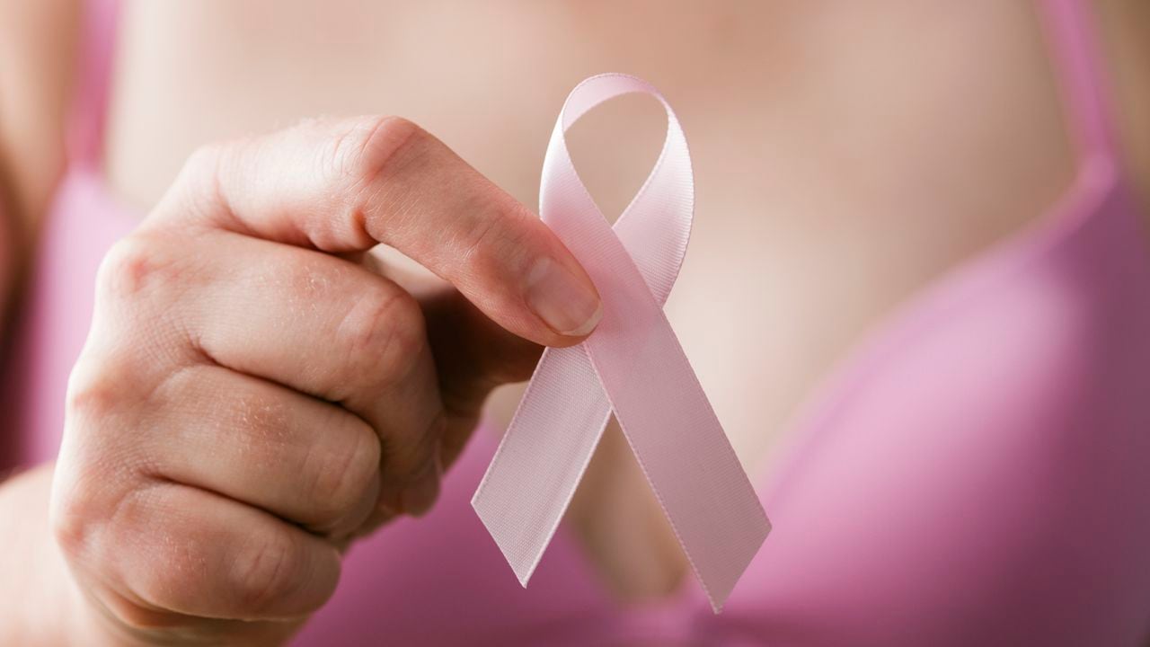 Mujer en sujetador rosa sosteniendo una cinta rosa, un recordatorio de la importancia del examen de mama en la atención médica para mantener y mantener un estilo de vida saludable y libre de cáncer