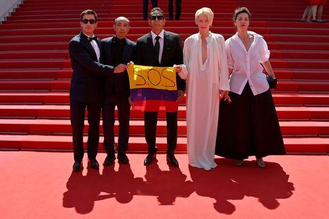 (From L) Colombian actor Juan Pablo Urrego, Thai director Apichatpong Weerasethakul, Colombian actor Elkin Diaz, British actress Tilda Swinton and French actress Jeanne Balibar pose with a Colombian flag reading "SOS" in support of anti-governments protests in Colombia as they arrive for the screening of the film "Memoria" at the 74th edition of the Cannes Film Festival in Cannes, southern France, on July 15, 2021. (Photo by John MACDOUGALL / AFP)