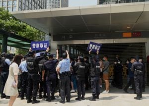TOPSHOT - Police officers look at people gathering at the Evergrande headquarters in Shenzhen, southeastern China on September 16, 2021, as the Chinese property giant said it is facing "unprecedented difficulties" but denied rumours that it is about to go under. (Photo by Noel Celis / AFP)