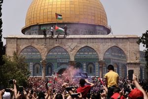 Palestinian Muslim worshippers wave the Palestinian and the Hamas flag during clashes with Israeli security forces in Jerusalem's al-Aqsa mosque compound, the third holiest site of Islam, on May 21, 2021. - Fresh clashes between Palestinians and Israeli police broke out at Jerusalem's Al-Aqsa mosque compound today, in the latest unrest at the sensitive religious site, AFP journalists and police said. Israeli police spokesman Micky Rosenfeld said officers were targeted by Palestinians who threw stones and had begun "riot" suppressing measures. AFP reporters said fierce clashes were ongoing at the site between police and Palestinians. (Photo by AHMAD GHARABLI / AFP)