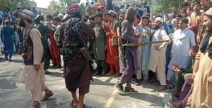 Taliban fighters and local people are pictured along the street in Jalalabad province on August 15, 2021. (Photo by - / AFP)