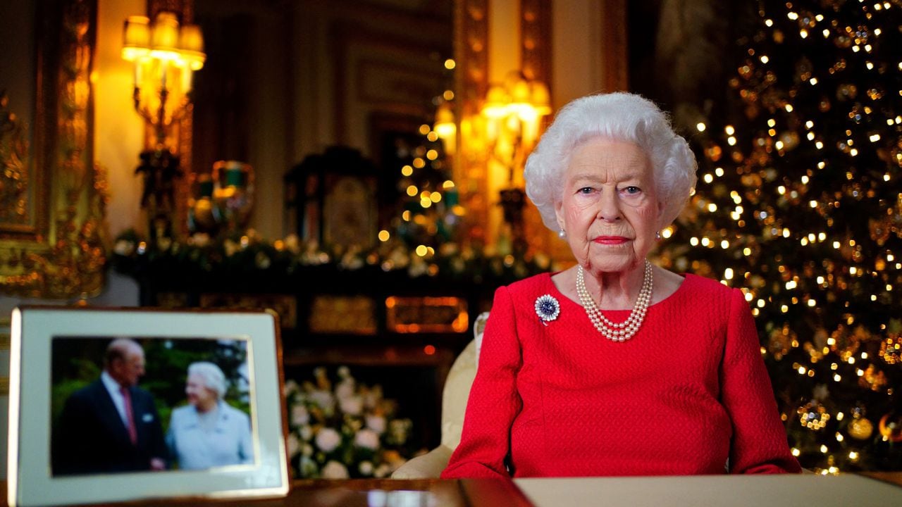 Una imagen publicada el 23 de diciembre de 2021 muestra a la reina Isabel II de Gran Bretaña posando para una fotografía mientras grababa su mensaje anual del día de Navidad, con una fotografía de ella y de su difunto esposo, el príncipe Felipe de Gran Bretaña, duque de Edimburgo, tomada en 2007 en Broadlands, para marcan su aniversario de bodas de diamantes, en el White Drawing Room del Castillo de Windsor, al oeste de Londres