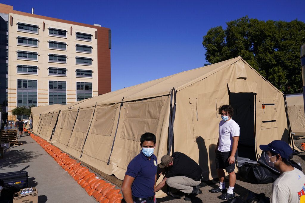 FILE - In this Monday, Dec. 21, 2020 file photo engineers and volunteers stand outside a mobile field hospital at UCI Medical Center, in Orange, Calif. The U.S. has reported by far the most virus infections and deaths. As of Tuesday, there had been 18,043,866 COVID-19 cases in the U.S. resulting in 319,466 deaths, according to Johns Hopkins University, with new cases rising over the past two weeks. (AP Photo/Jae C. Hong, File)