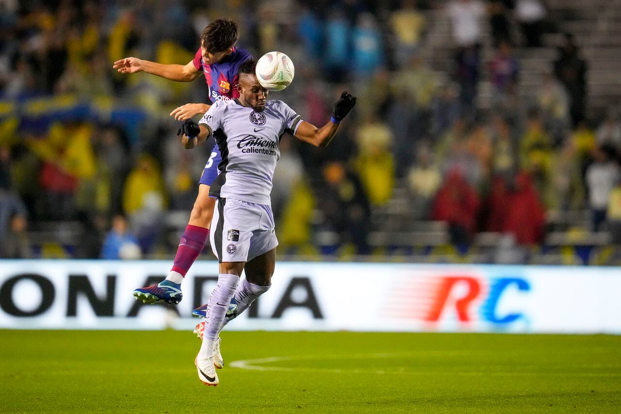 Club America's Julian Quiñones, right, and Barcelona's Pau Cubarsi go up for the ball during the first half of a club friendly soccer match, Thursday, Dec. 21, 2023, at the Cotton Bowl in Dallas. (AP Photo/Julio Cortez)