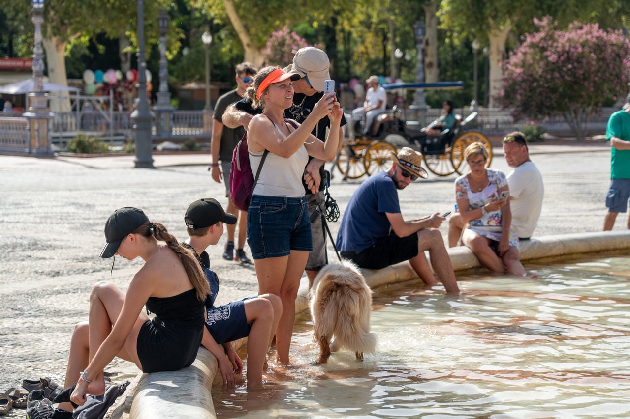 Los turistas se refrescan en la fuente de la Plaza de España, en plena ola de calor el 07 de agosto de 2023 en Sevilla (Andalucía, España). La Agencia Estatal de Meteorología (Aemet) ha activado este martes el aviso naranja por altas temperaturas, de 13.00 a 21.00 horas en Sevilla.