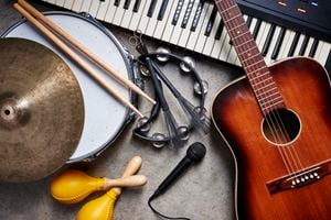 a group of musical instruments including a guitar, drum, keyboard, tambourine.