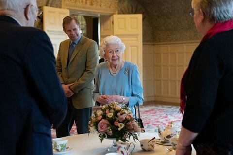 estida con un traje azul claro y adornada con un collar de perlas y un bastón en la mano, la reina cortó un pastel preparado para la ocasión (Photo by Joe Giddens / POOL / AFP)