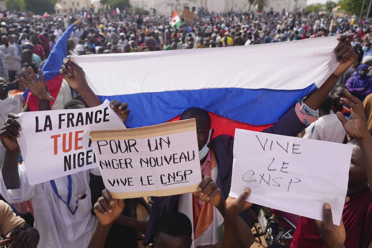 Los nigerianos que sostienen una bandera rusa y pancartas participan en una marcha convocada por los partidarios del líder golpista, el general Abdourahmane Tchiani, en Niamey, Níger, el domingo 30 de julio de 2023.