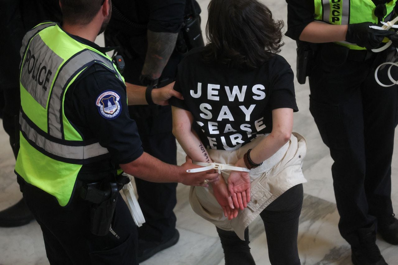 Un manifestante es detenido por un oficial de policía mientras la gente se manifiesta mientras participan en la desobediencia civil y una protesta pidiendo un alto el fuego en Gaza, en Capitol Hill, en Washington
