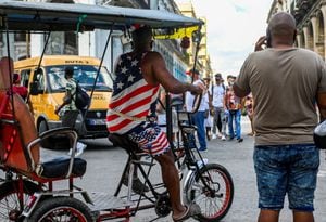 Un hombre vestido con una camiseta y un pantalón corto con la bandera de EE. UU. pasea en su bicitaxi por una calle de La Habana, el 17 de mayo de 2022.