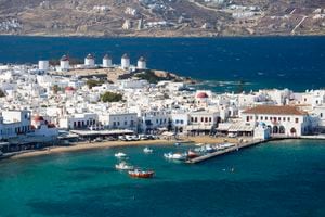 View over the harbour from hillside, row of historic windmills (kato mili) prominent, Mykonos Town (aka Hora, Chora), Mykonos, Cyclades Islands, South Aegean, Greece, Europe.