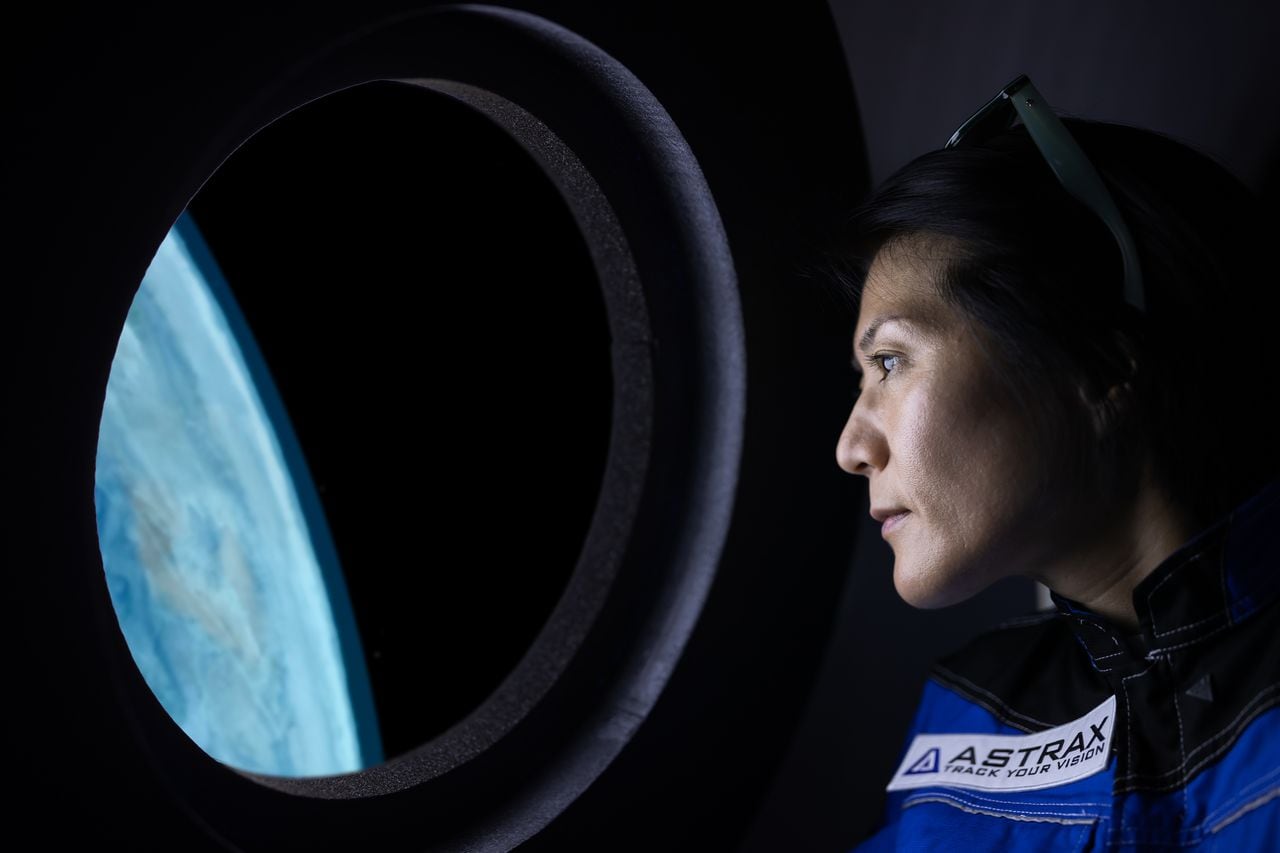 A commercial space traveler looking at the earth throughout  the window at inside of the spaceship.