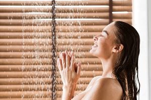 Woman Taking Shower Enjoying Water Splashing On Her, Side View