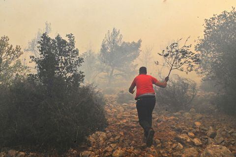 Los lugareños ayudan a los bomberos mientras intentan extinguir un incendio forestal que arde cerca del pueblo Vlyhada cerca de Atenas el 19 de julio de 2023 en Atenas, Grecia.
