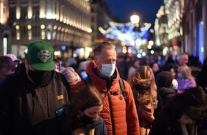 Los compradores, algunos con cubiertas para la cara, cruzaron Oxford Street en el centro de Londres el 4 de diciembre de 2021, ya que el uso obligatorio de máscaras en las tiendas se ha reintroducido en Inglaterra a medida que aumentan los temores sobre la variante Omicron de Covid-19. (Foto de Daniel LEAL / AFP)