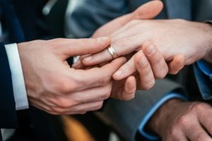 Close-up of a gay's hand placing the ring on his friends hand during their gay wedding ceremony
