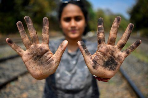 En esta fotografía tomada el 11 de marzo de 2021, la zoóloga Hycintha Aguiar muestra sus manos cubiertas de hollín tras manipular el carbón caído a las vías del tren de carga en la estación de tren de Kulem, en Goa. Foto de Indranil Mukherjee / AFP