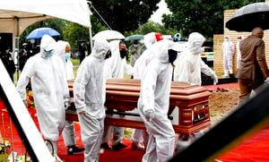 In this photo provided by the South African Government Communications and Information Services (GCIS) pallbearers carry the coffin in Witbank, South Africa, Sunday, Jan. 24, 2021, at the funeral of Cabinet minister Jackson Mthembu, who died of COVID-19 last week. Police are investigating the premier of the Mpumalanga province Refilwe Mtsweni-Tsipane for failing to wear a mask and for hugging a police officer at the public funeral. (Kopano Tlape/South African Government Communication and Information Services via AP)