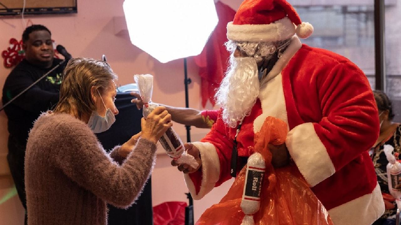 Un hombre vestido como Papá Noel entrega un obsequio a una mujer en un asilo de ancianos, en la ciudad de Nueva York.