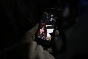 A person watches a video on a mobile phone showing a man pointing at Argentine Vice-President Cristina Fernandez de Kirchner outside her residence in Buenos Aires on September 1, 2022. - A man was arrested Thursday in Argentina for pointing a gun at Vice-President Cristina Kirchner as she arrived at her home, said Security Minister An�bal Fern�ndez. (Photo by Luis ROBAYO / AFP)