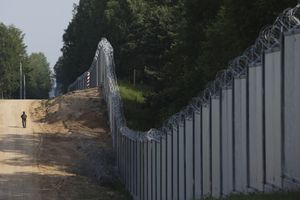 FILE - A Polish border guard patrols the area of a built metal wall on the border between Poland and Belarus, near Kuznice, Poland, on June 30, 2022. Poland is deploying thousands of troops to its border with pro-Russian Belarus, calling it a deterrent move as tensions between the neighbors ratchet up. Officials in Belarus have been making hostile comments about Poland, a European Union and NATO member. (AP Photo/Michal Dyjuk, File)