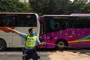 Un oficial de policía inspecciona después de un accidente en una carretera en Hong Kong, el viernes 24 de marzo de 2023. Cuatro autobuses de pasajeros y un camión chocaron el viernes cerca de un túnel de carretera de Hong Kong, hiriendo a decenas de personas. (AP Photo/Louise Delmotte)