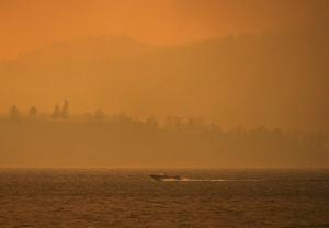 Un bote viaja a lo largo del lago Okanagan mientras el humo del incendio forestal McDougall Creek cubre el área, el viernes 18 de agosto de 2023, en Kelowna, Columbia Británica. (Darryl Dyck/The Canadian Press vía AP)